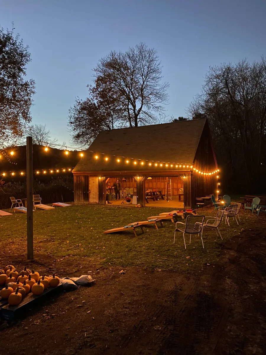 An autumn evening gathering beside a barn strung with warm lights